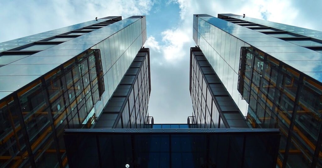 Low-angle view of sleek, modern skyscrapers with glass facades under a blue sky.