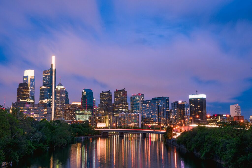 Gorgeous view of the Philadelphia skyline against a vibrant evening sky, reflected on the river.